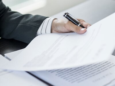 A law attorney reviewing legal documents at a desk with a legal contract and a pen.