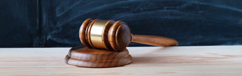 Judge's gavel on a desk in front of a blackboard