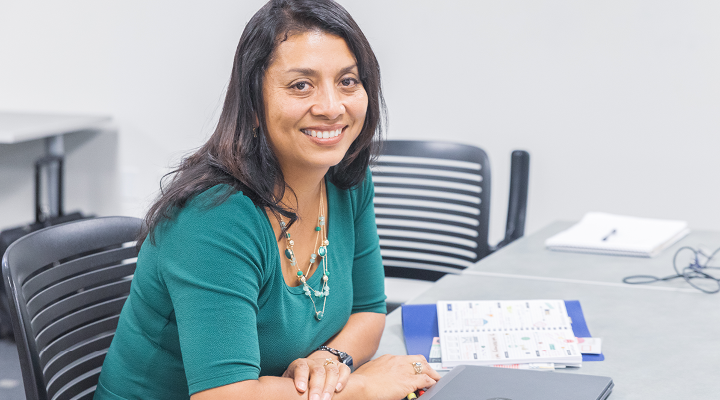 Woman in green shirt smiling while working at classroom table