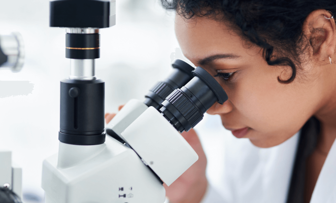 Woman with curly hair looking into a microscope