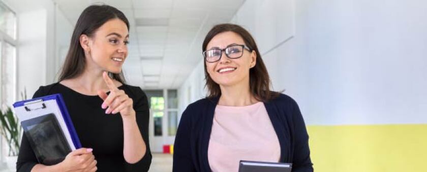 Two teachers walking down the hallway and talking