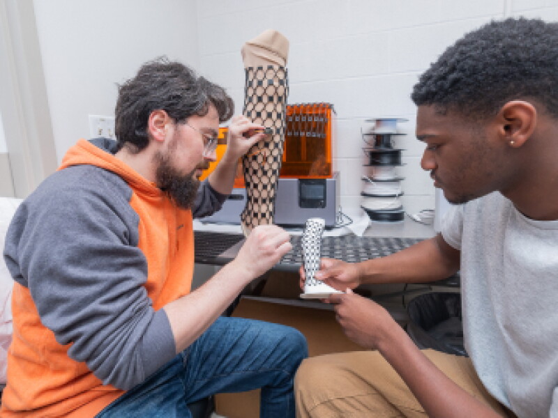 Close-up of two CWRU students working on a device prototype.