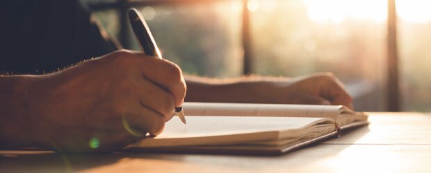 Hand writing in journal on a desk
