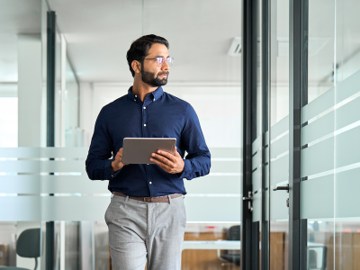 Busy professional businessman going in hallway holding digital tablet thinking of work
