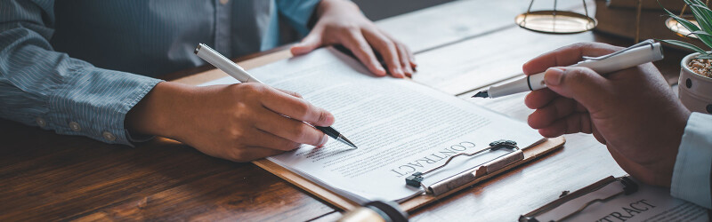 two people with pens in hands looking over a contract