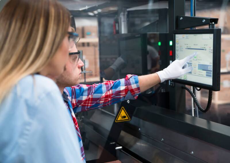 Female and male manufacturers reading screen