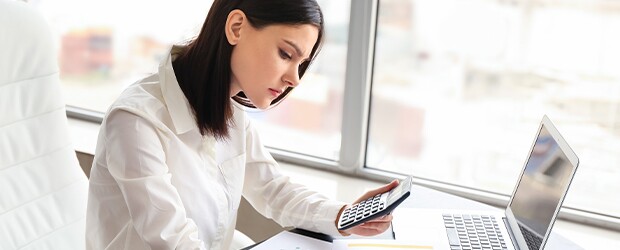 Female accountant working at her desk with calculator and computer