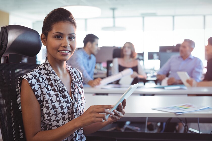 Female professional in a patterned blouse sits to the side of a conference table