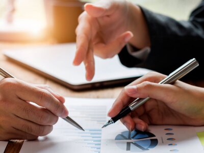 Financial analyst analysis business financial report on digital tablet during discussion at meeting.