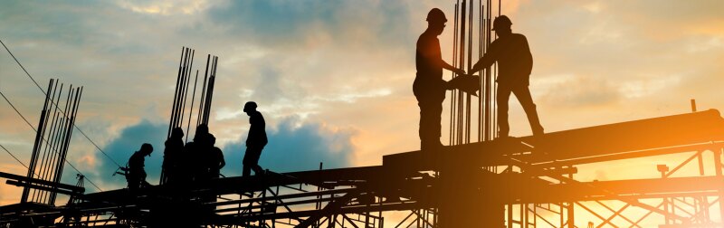 Silhouette of engineer and construction team working at site over blurred background sunset.