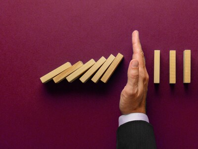 Insurance, hand stopping a series of dominos from falling