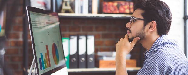 man sitting at desk looking at metrics on screen