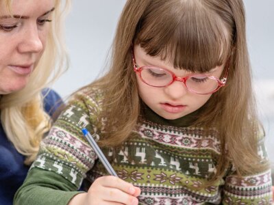 Young girl with Down Syndrome works with her teacher in the classroom.