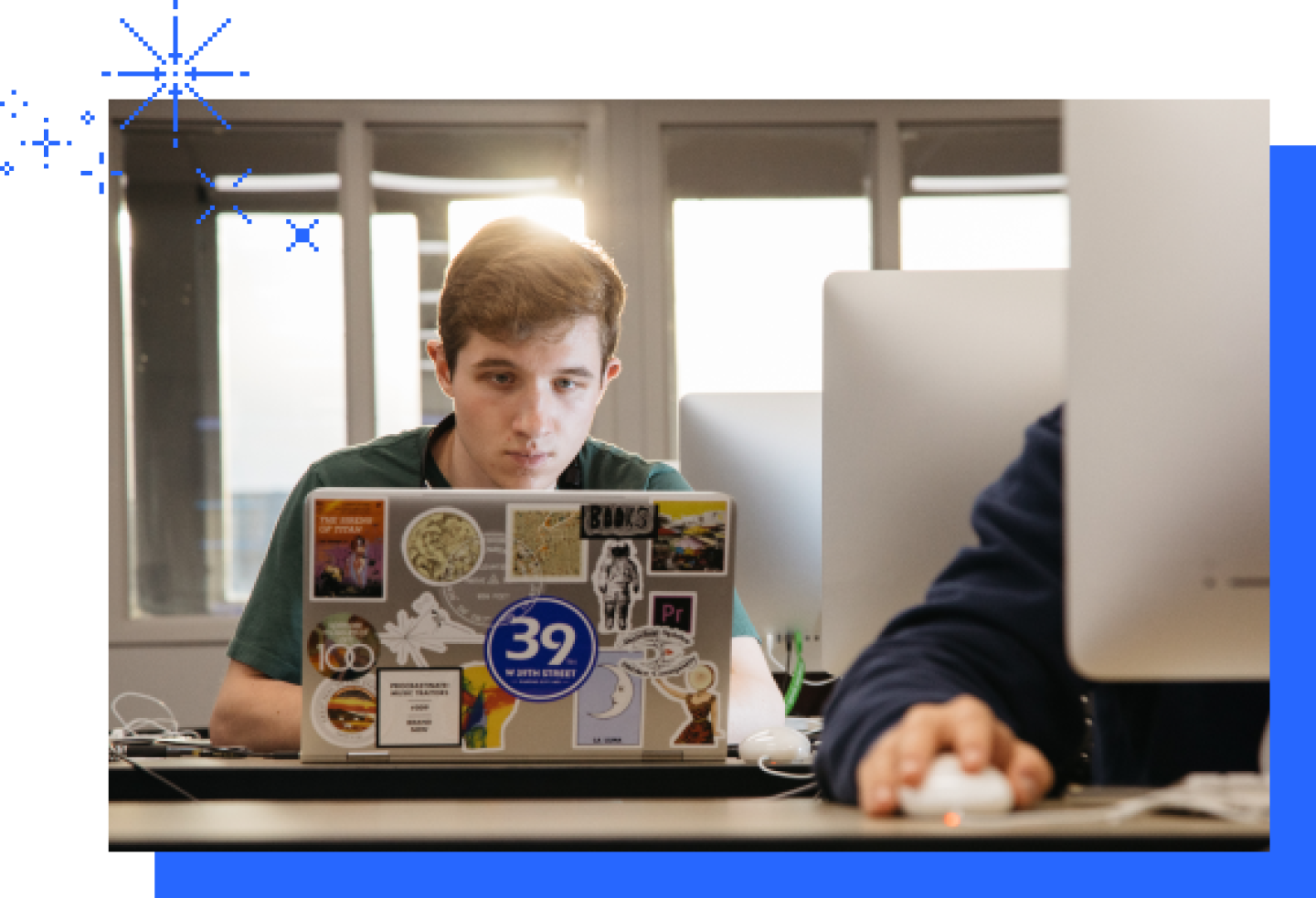 A close-up of a male KU student on a laptop with stickers attached to the laptop.