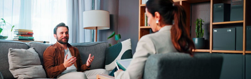 Happy man, patient and talking with therapist for counseling, rehabilitation or therapy session.
