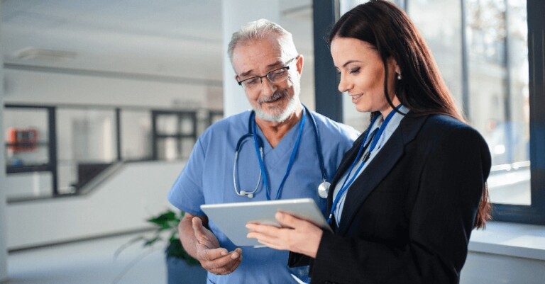 Woman in blazer showing tablet to man in scrubs
