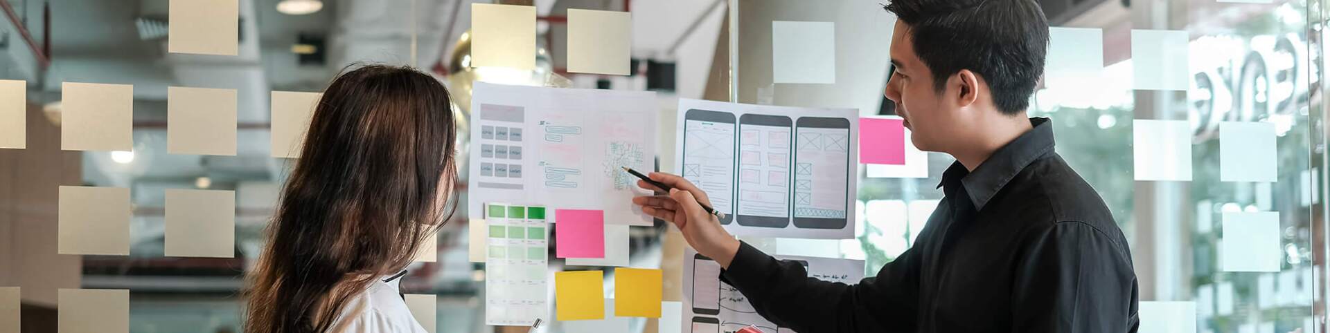 Two designers collaborating at a glass wall