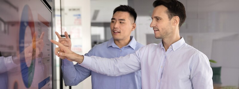 Colleagues analyzing marketing report on presentation TV board, pointing at statistic data