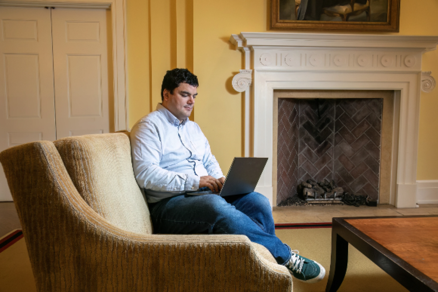 man sitting in a large comfy chair with tap top in his lap