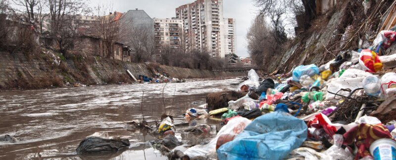 Landfill overflowing into river in an urban environment
