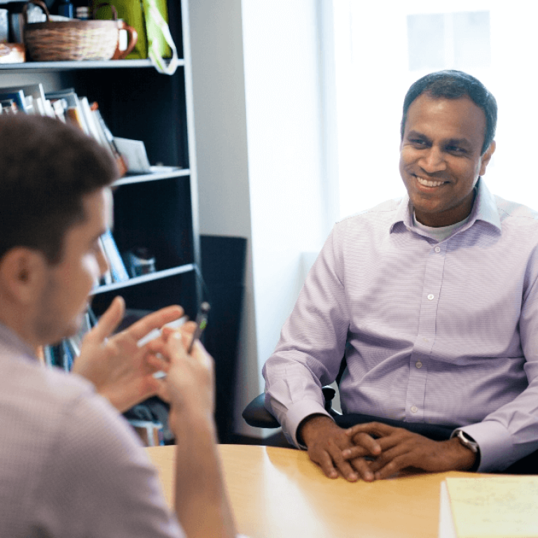 Two men speaking to each other across table