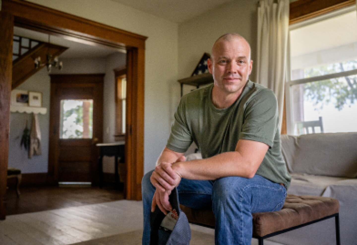 A male military veteran sitting in living room with arms crossed.