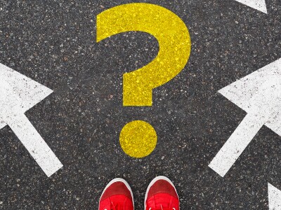 A yellow question mark painted on the ground next to arrows pointing in various directions.