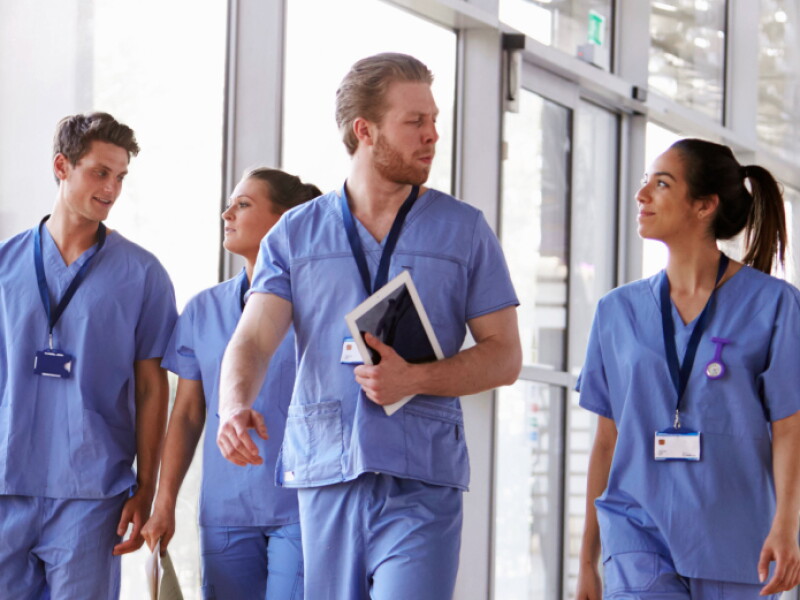 Four nurses talking while walking through a sunny hallway