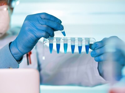 someone with gloves on dropping liquid into tubes