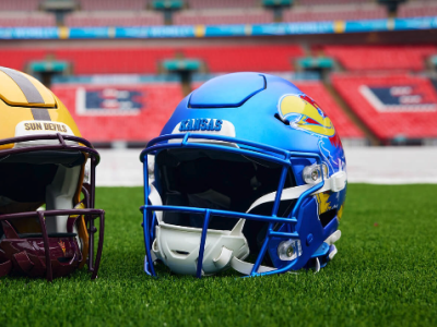 Kansas Jayhawks helmet sits opposite an Arizona State University Sun Devils helmet on the turf of Wembley stadium.