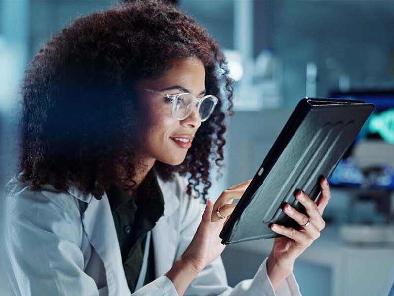 Medical professional reviews data on a tablet.
