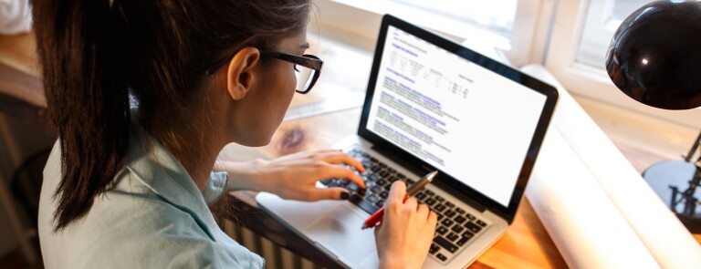 Young female blogger working at home.She sitting in her working room and typing something on laptop.