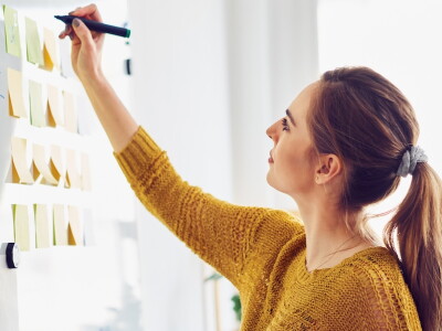 A woman creates a wire frame on a whiteboard for a learning design exercise