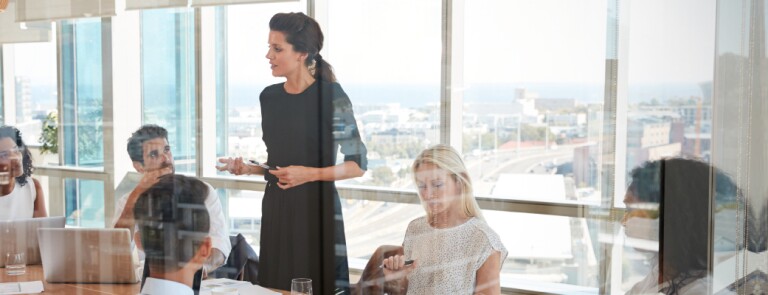 Woman leads a meeting standing up at the table in conference room