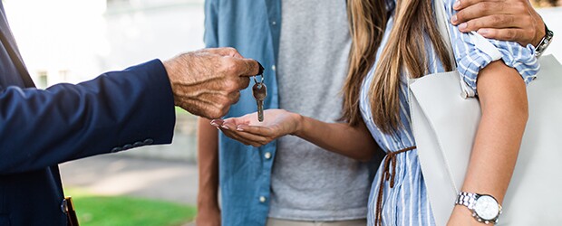 Man hands a pair of keys over to a couple