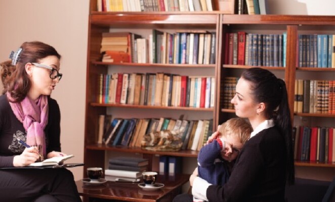 mother holding baby talking to counselor in office