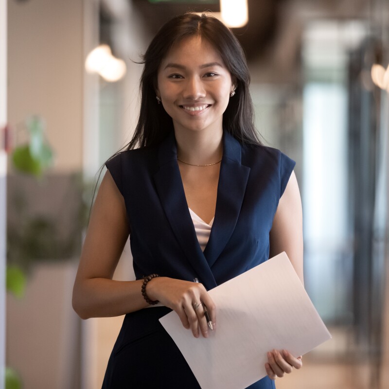 Female professional stands holding a manila envelope in a hospital