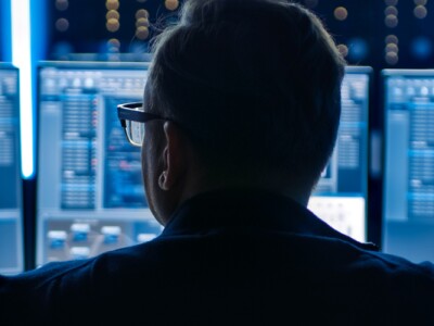 Professional IT Programer Working in Data Center on Desktop Computer with Three Displays.