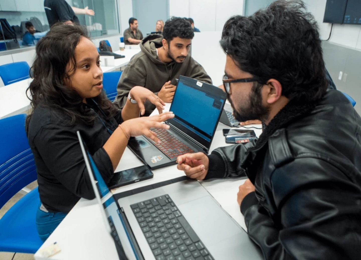 Three cybersecurity students collaborating with laptops
