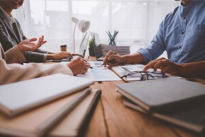 Business colleagues sit around an office table discussing details in a balance sheet.