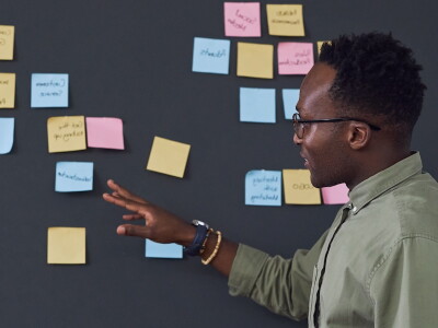 Man stands in front of a chalk board reviewing curriculum plans in a faculty staff meeting