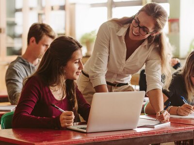 A teacher engaging with a student using a laptop