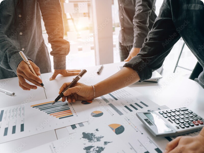 group of three standing at a table, going over graphs and spreadsheets