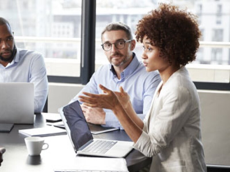 Woman speaking to team around conference table
