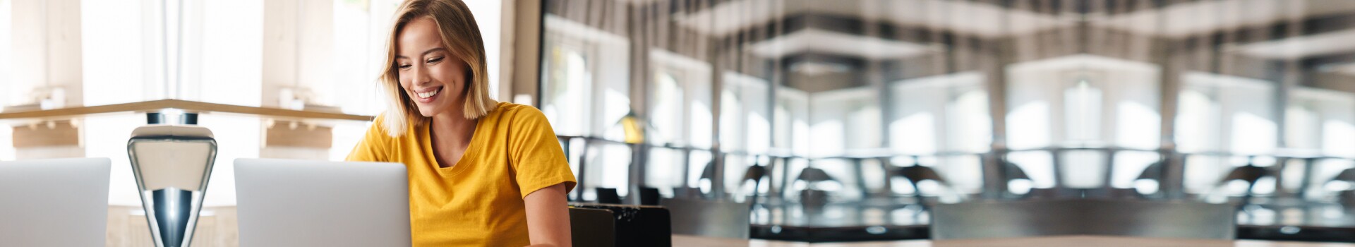Woman in yellow shirt works on laptop