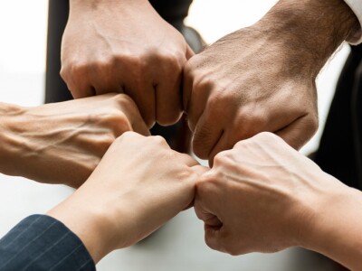 Five people form a circle with their fists for a team fist bump.