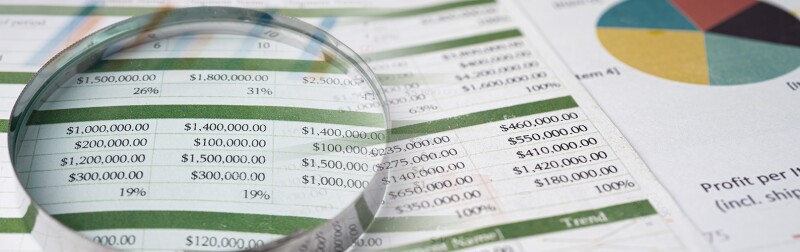 Magnifying glass examining spreadsheets