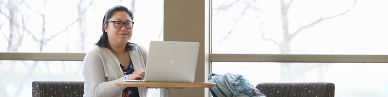 Confident student works on master’s in health care analytics on her laptop computer.