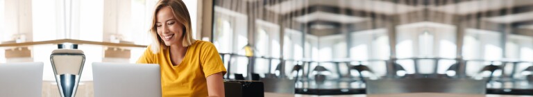 Woman in yellow shirt works on laptop