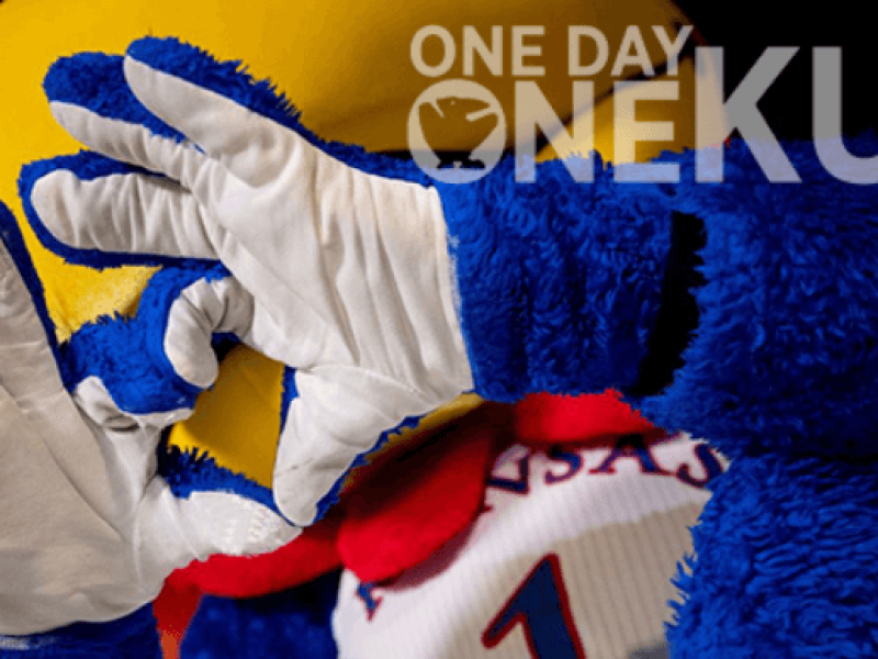 KU Jayhawk mascot holding hands in the shape of a heart